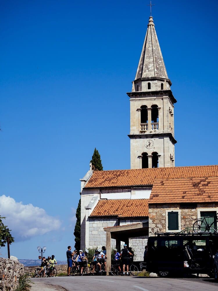 Cycling group by a historic church tower during a bike tour in Croatia